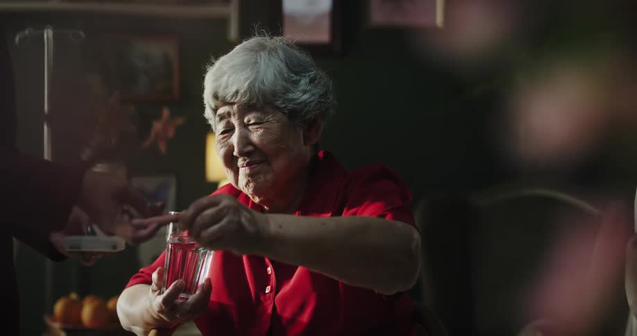 An older woman takes medication with water