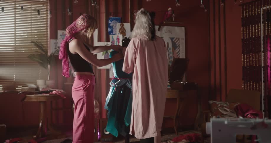 Two female fashion designers assembling a dress on a mannequin