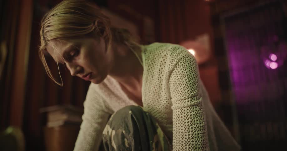 Blonde woman wearing yellow sweater gazes down indoors
