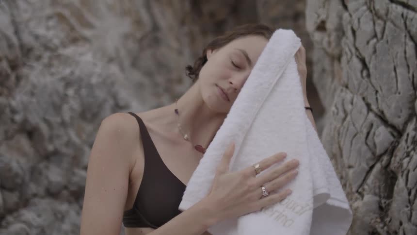 Young woman wearing a swimsuit dries with a towel