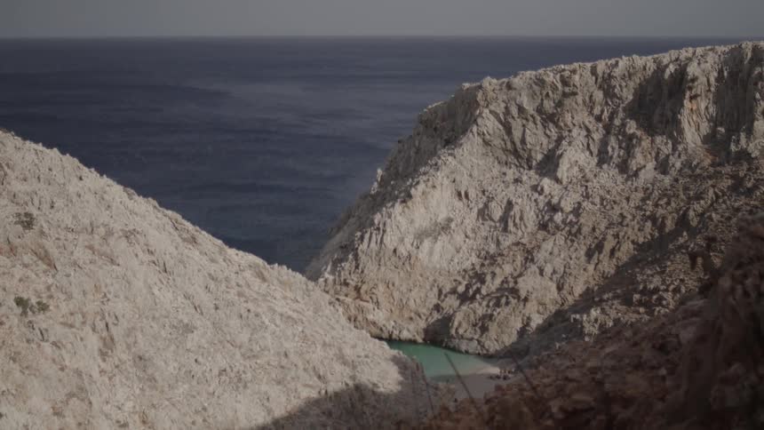 Waves roll into shore with mountains along the coast