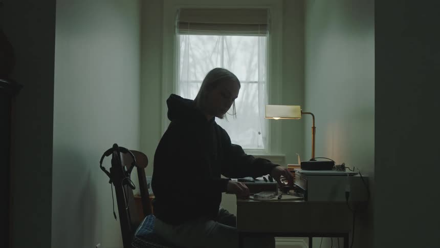 Young musician wearing a hoodie writes a label and applies it to a cassette tape holder