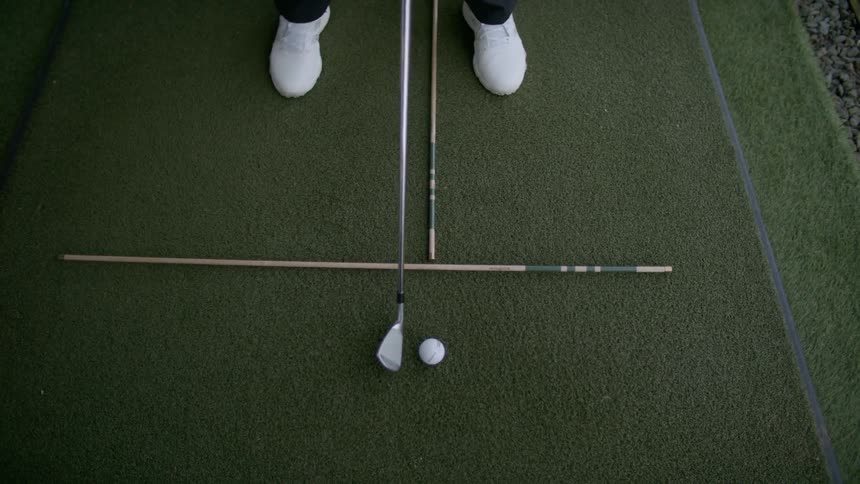 Golf ball being hit with a golf club from a the green at a driving range