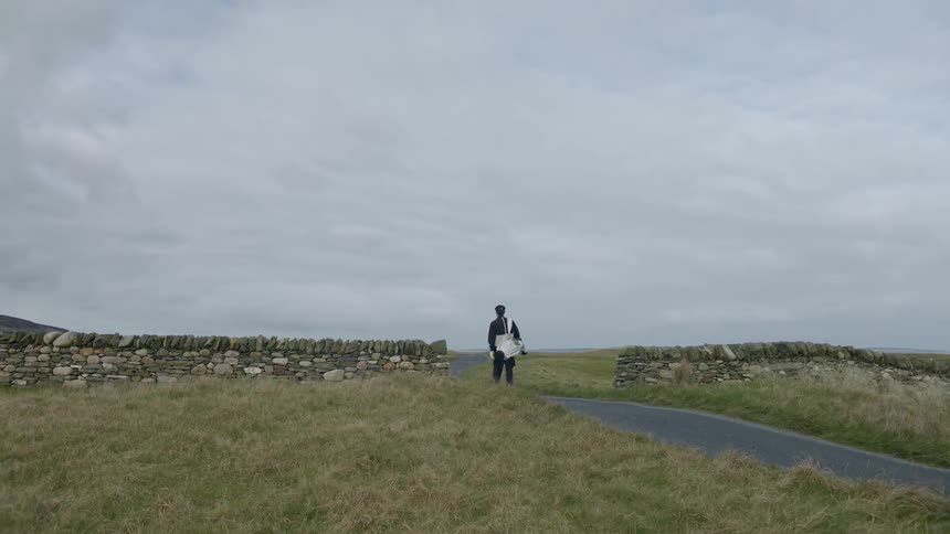 A person walks down a small concrete path between two rock walls