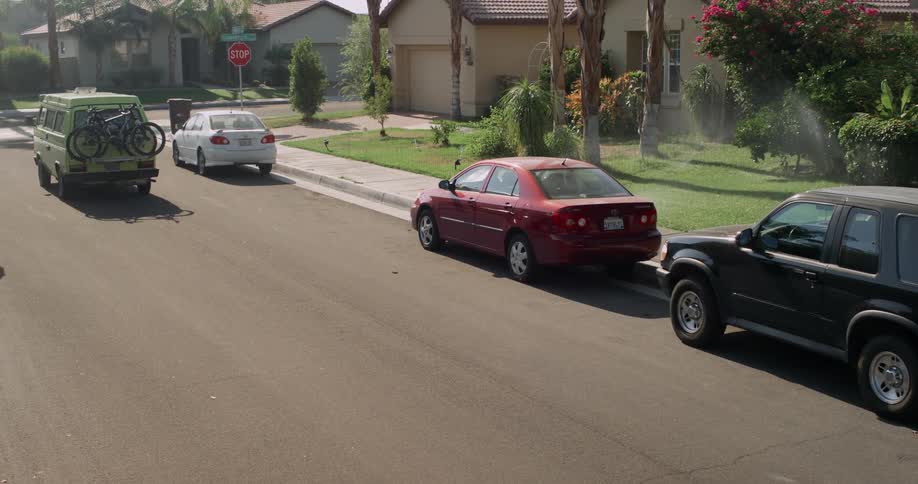 A van driving through the streets of a suburban neighborhood on a sunny morning