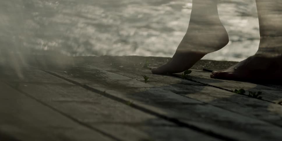 A woman walks on a dock as the sunshine glistens off of water