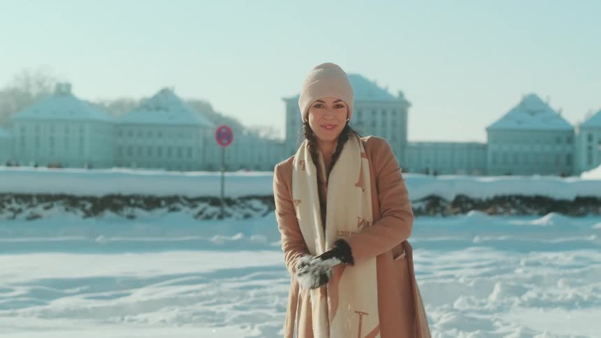 Woman in the snowy ground picking up snow with her hands forming a snowball and playing