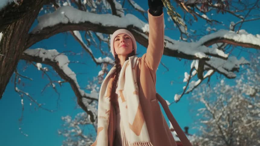 Young beautiful woman walks under a tree at winter
