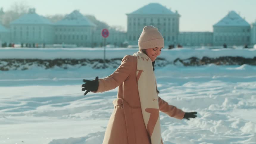 A young woman walks in deep snow and makes a snowball