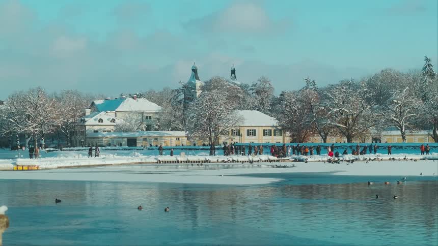 Panorama of a park with a lake in winter with snow and people observing
