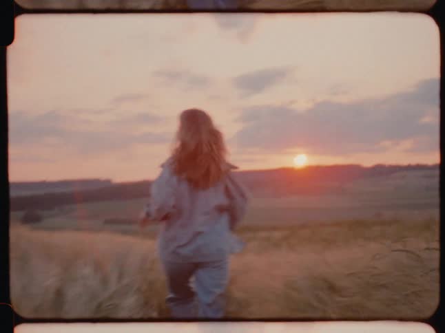 Back of a lady running on grass at sunset