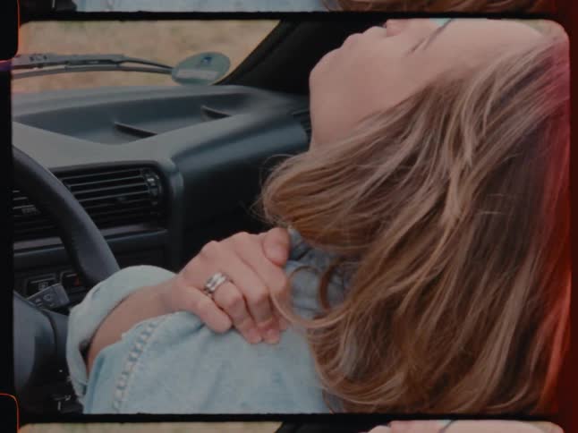 Woman sitting in the car seat looking up with one hand on her own shoulder