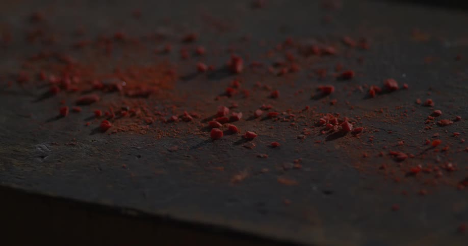 Red shavings vibrate on a tabletop