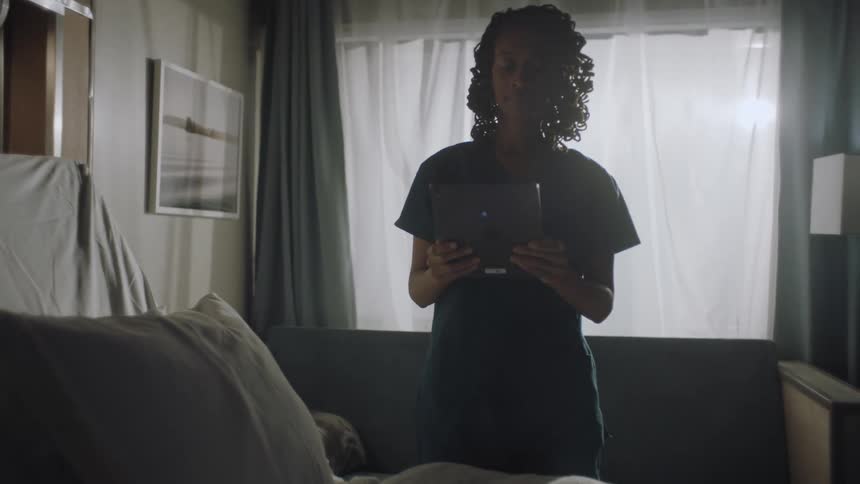Nurse using a tablet checks an empty hospital room