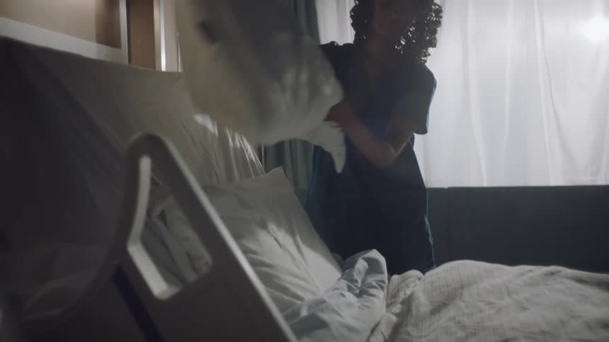 Nurse makes the hospital bed and fluffs the pillows