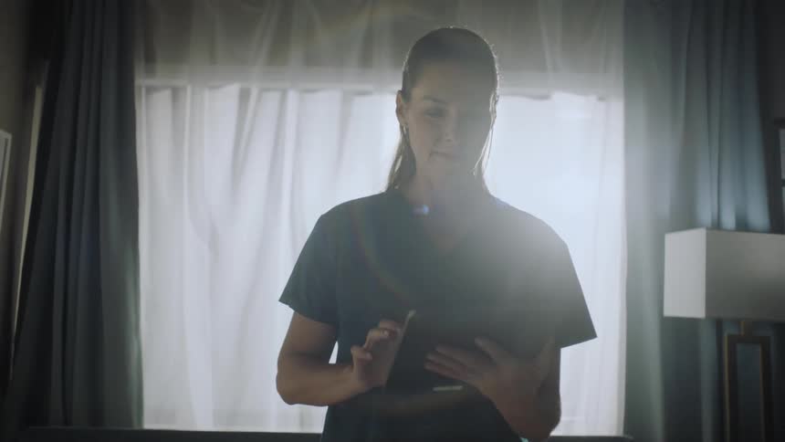 Nurse standing in a room using a tablet
