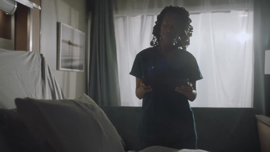 Nurse using a tablet checks an empty hospital room
