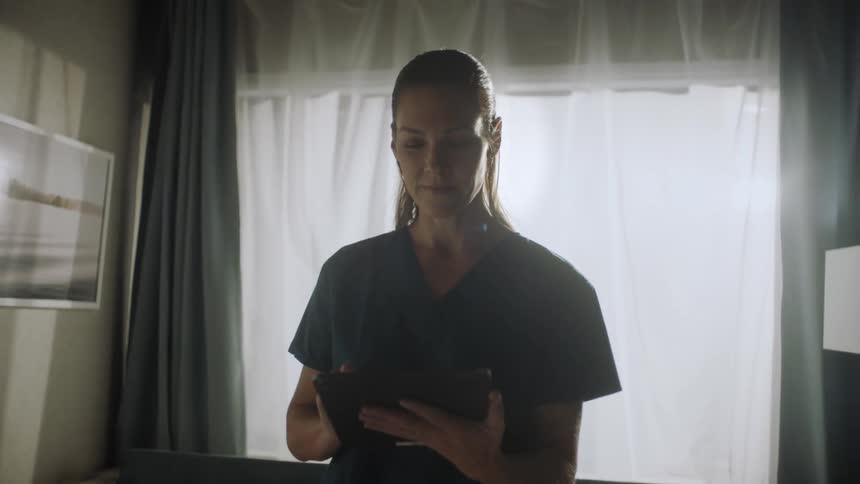 A doctor in a hospital room typing on a tablet