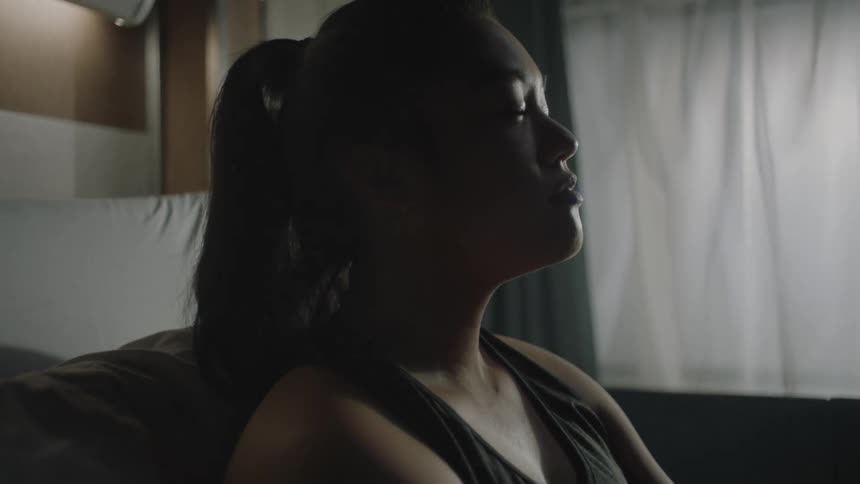 Portrait of a woman taking a deep breath while sitting on a bed