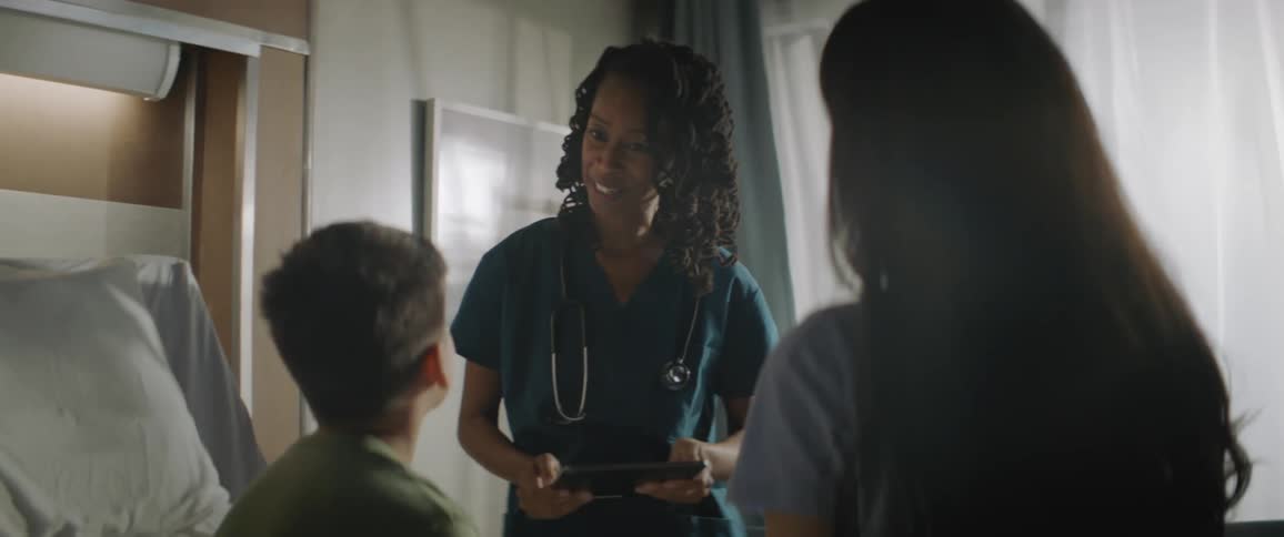 Nurse talks to a boy and his mother in a hospital room