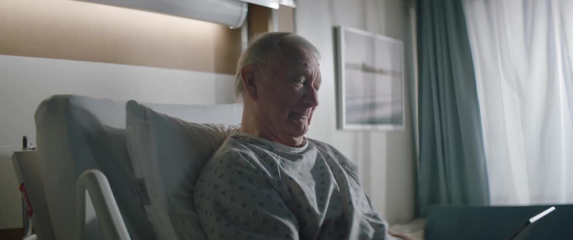 Elderly person sitting on a hospital bed using a tablet