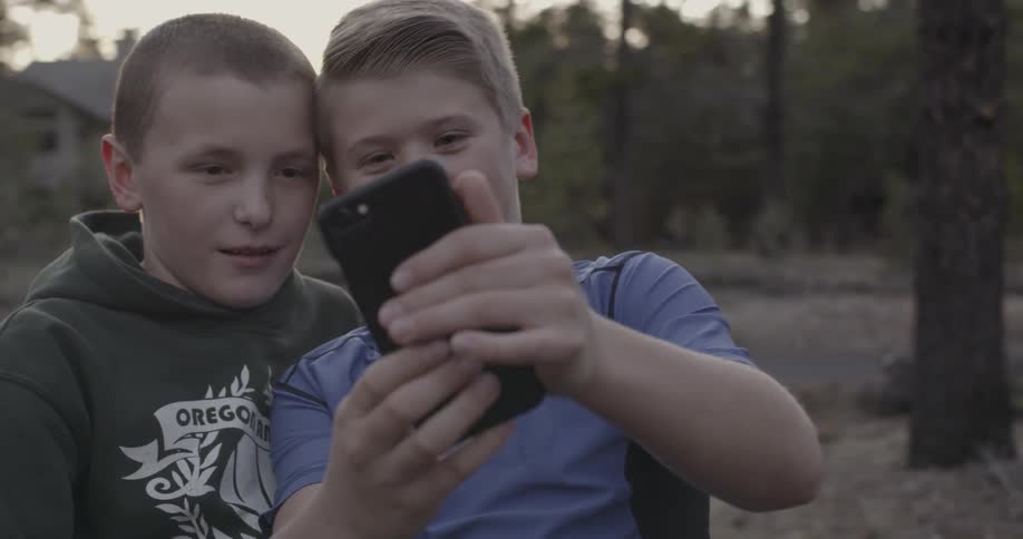 Two boys laugh at what's displayed on a phone