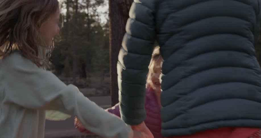 Three girls hold hands and jump around in a circle