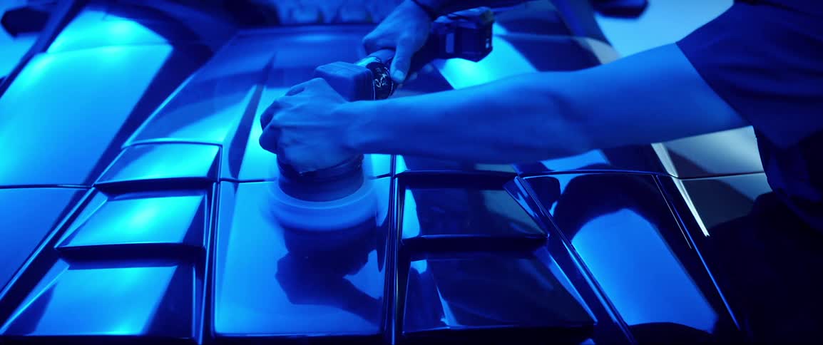 Closeup on the arms of a man polishing the top of a lamborghini