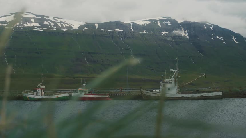 Docked boats on a river near a mountain range