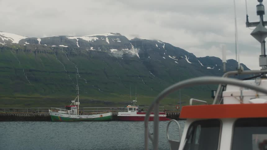 Some boats on a river next to a mountain with snow on top