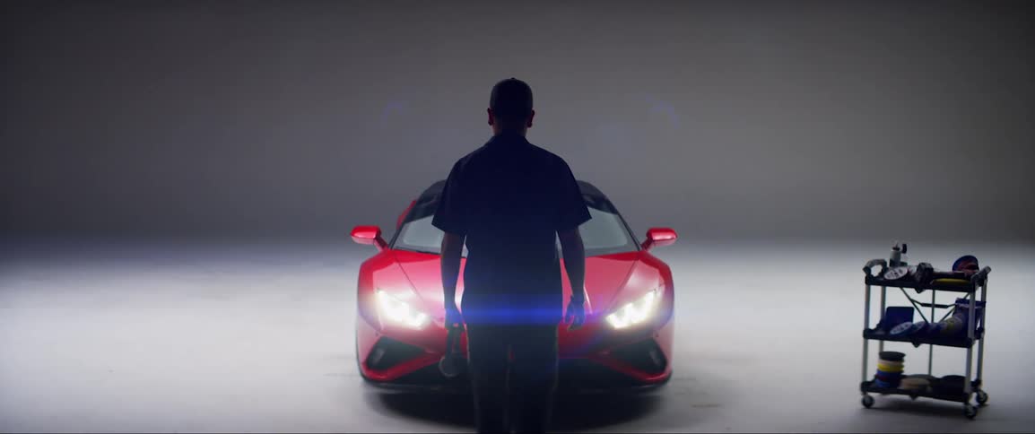 Man walking towards a red lamborghini inside a studio