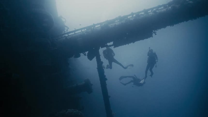 Divers at the bottom of the sea amidst wreckage