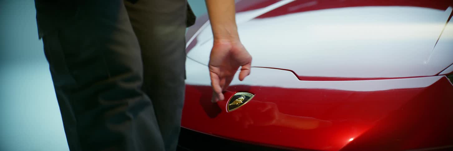 Man walking in front of a red lamborghini