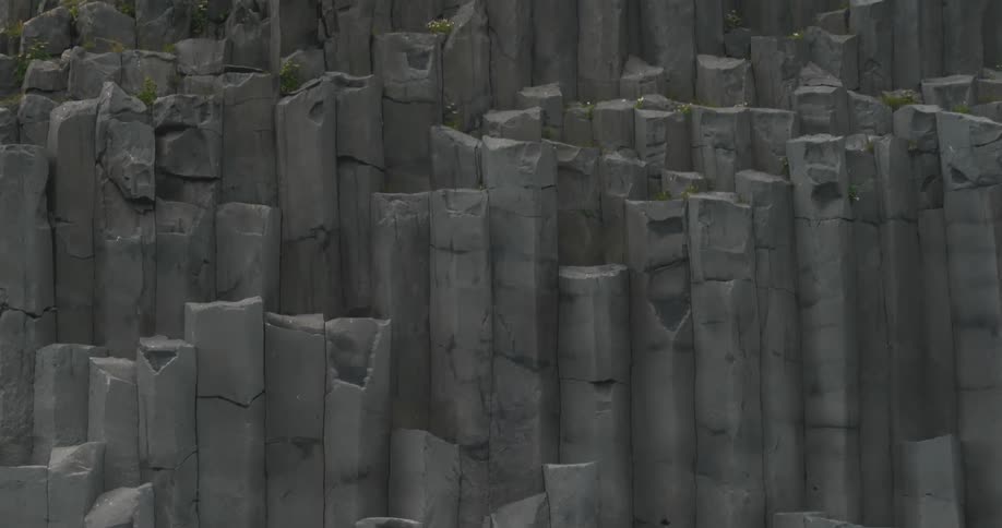 A rock formation with separate rectangular stones and some grass on top