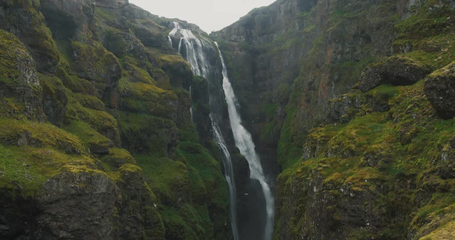 Waterfall surrounded with moss covered rocky cliff walls