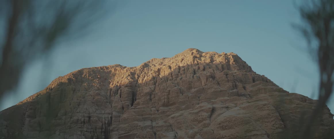 Panorama of a rocky mountain in a valley under a mornings blue sky