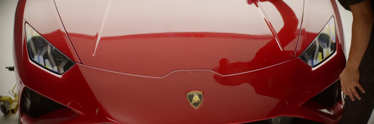 Man wiping the front part of a red lamborghini