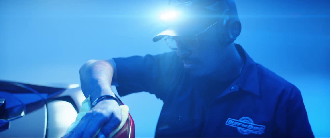 Portrait of a man wiping the rear of a red car