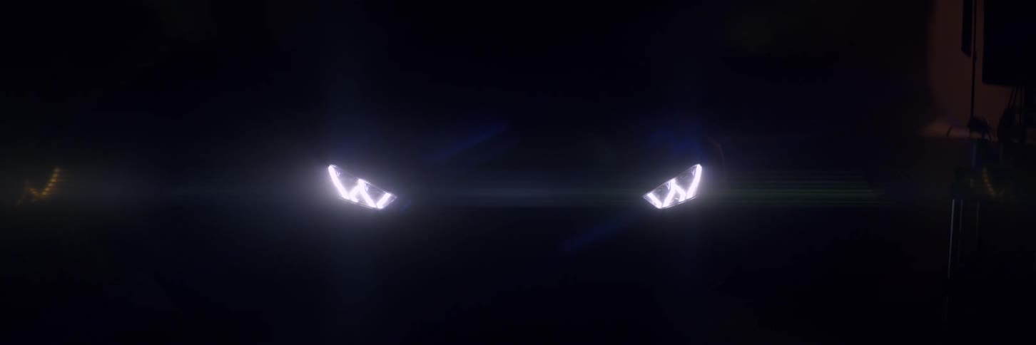 Sports headlights illuminated on the front of a ferrari in a dark room