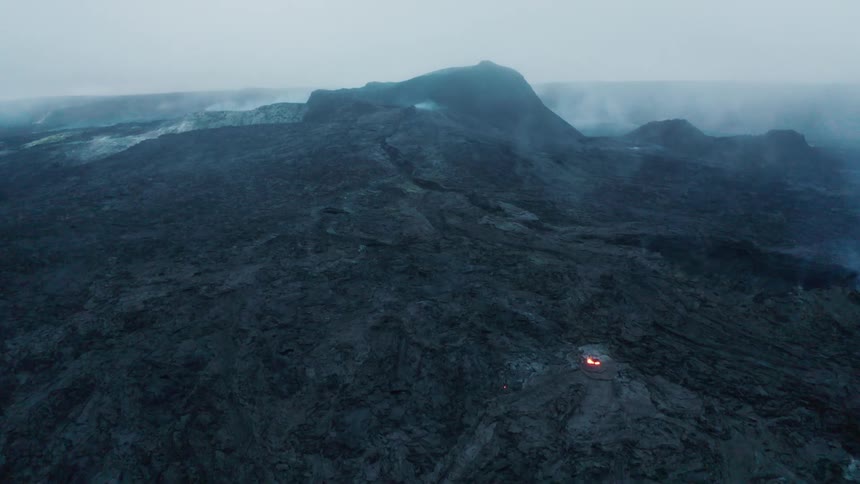 Hot lava glows at the top opening of a volcano