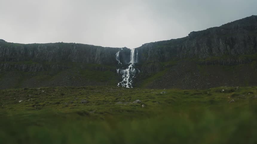 A waterfall pours off the mountain
