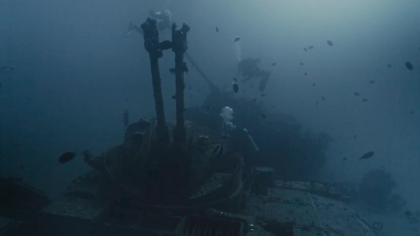 Divers swimming near a tank at the bottom of the sea
