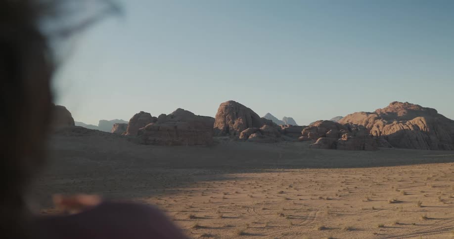 Woman facing away enjoying the view of rocks in the midst of the desert
