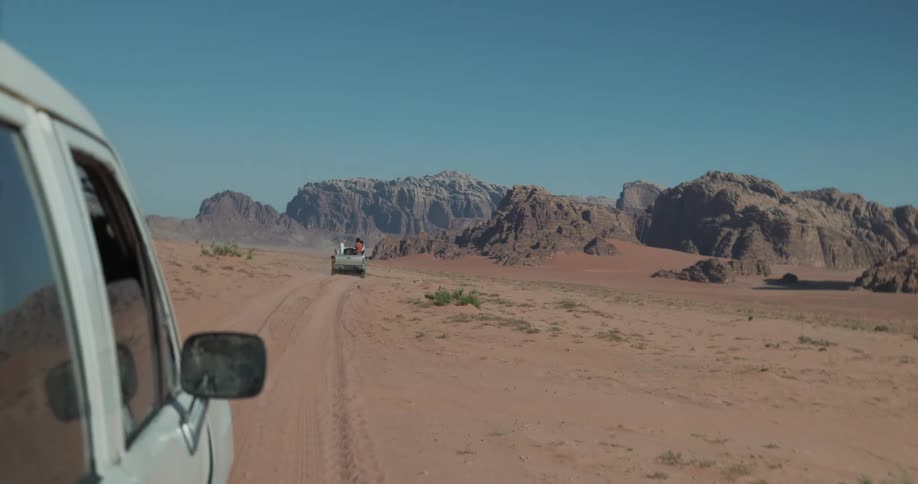 Vehicles driving through the desert with mountain chairs during hot summer day