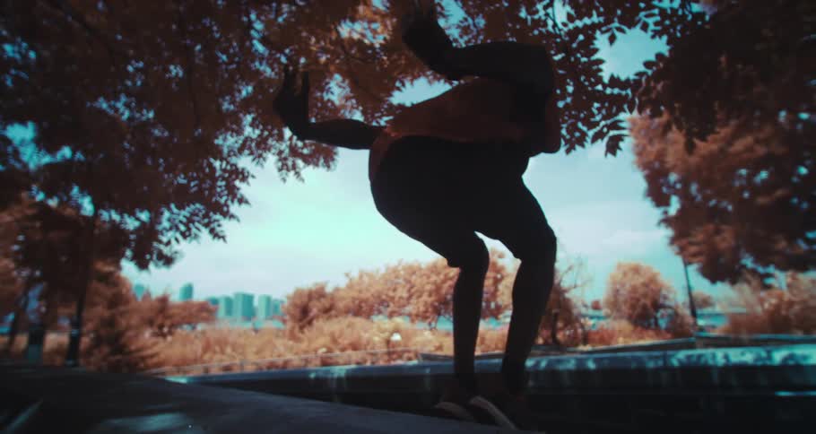Man jumping a corner in the middle of a park supporting his hands on the handrail and concrete