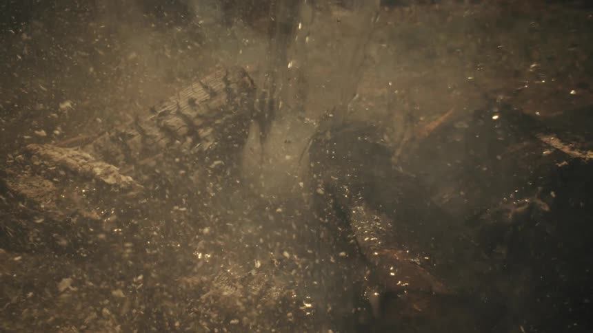 A lot of water falling on a fire with wood and putting out the fire