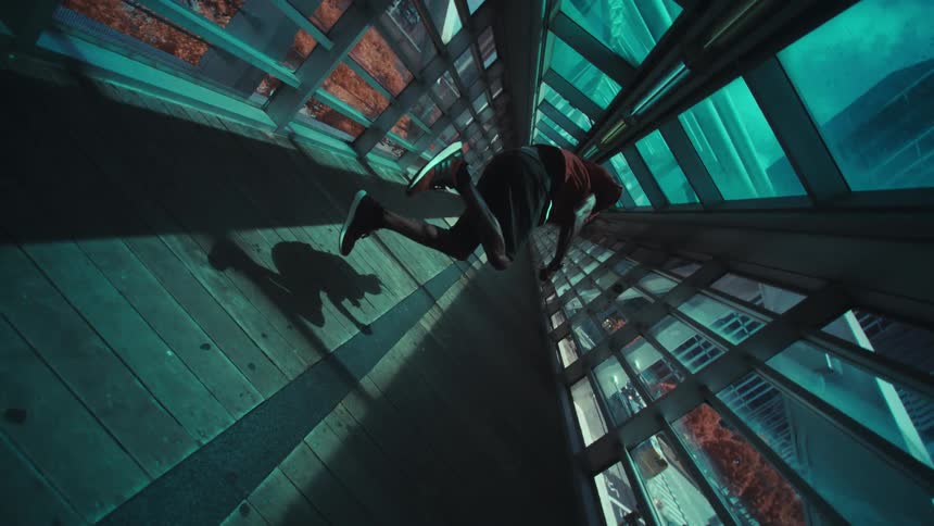 A man is on a path full of windows and does an acrobatic jump