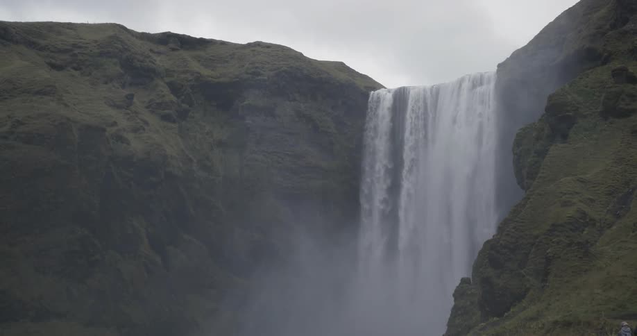 Hikers walk near a large waterfall