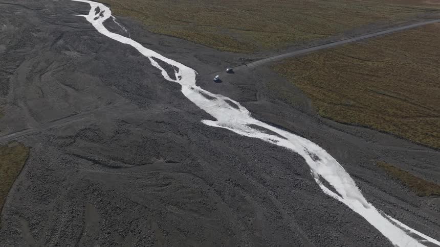 Aerial view of vehicles driving near a frozen river in the field