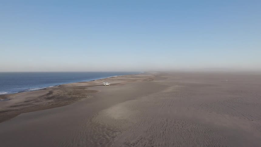 An aerial view of a flat plateau in a coastal region with the ocean below and the horizon in the distance in the daytime